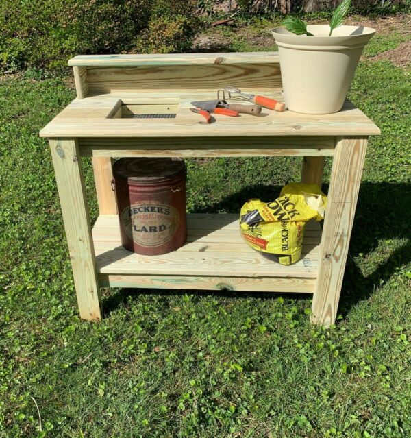 Front view of potting table with garden hand tools, potted plant, and potting supplies.