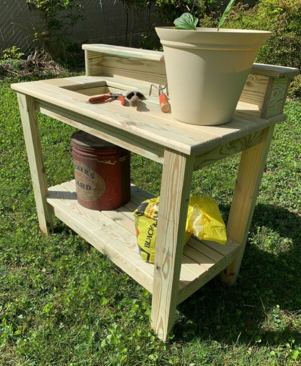 Potting table with potted plant, potting supplies, and garden tools.